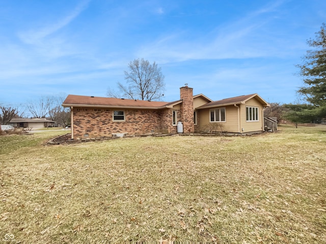 rear view of property with brick siding, a chimney, and a yard