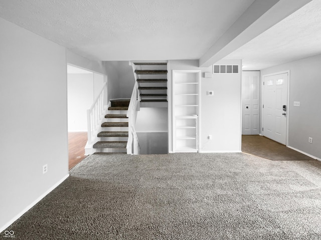 unfurnished living room with carpet floors, visible vents, stairway, and a textured ceiling