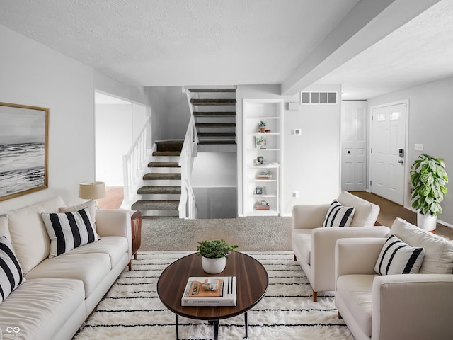 living room with a textured ceiling, stairway, and visible vents