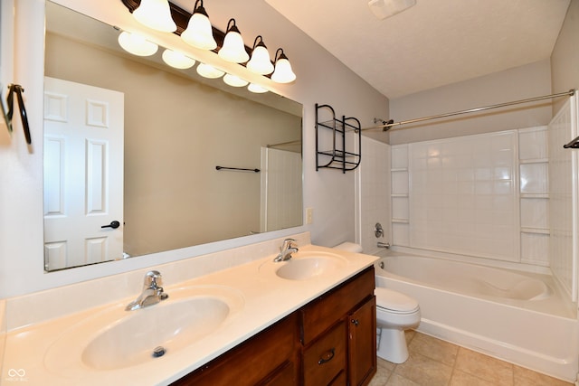 full bath with toilet, double vanity, a sink, and tile patterned floors