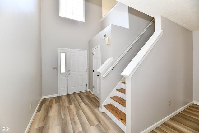 entrance foyer featuring a high ceiling, stairs, baseboards, and wood finished floors