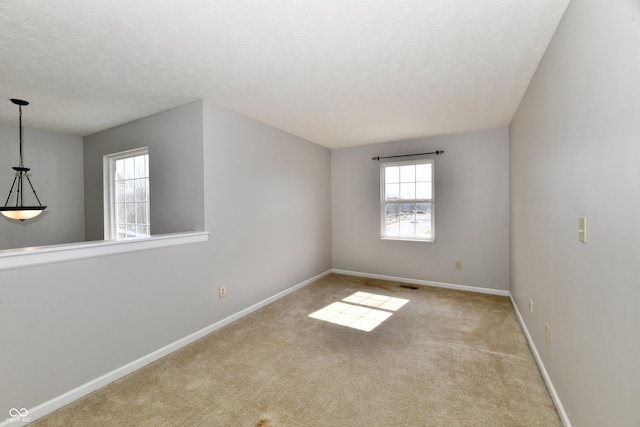 empty room featuring carpet, visible vents, baseboards, and a textured ceiling