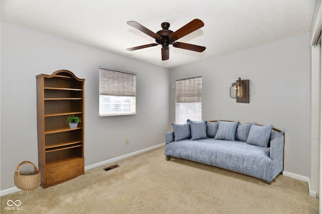 living area with carpet floors, a ceiling fan, visible vents, and baseboards