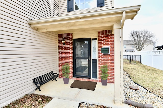 property entrance featuring fence and brick siding