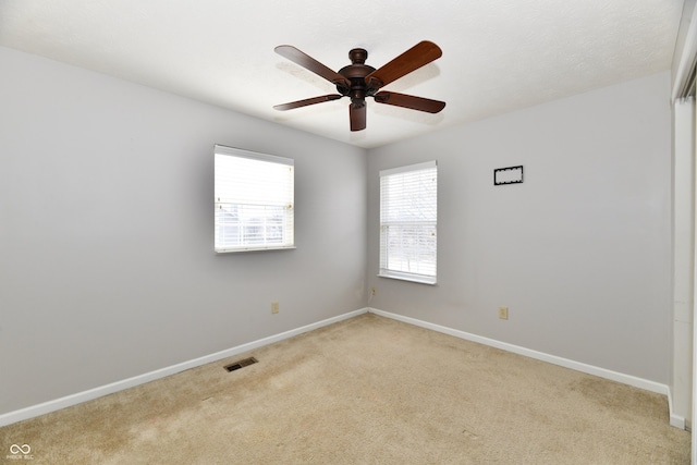 spare room with visible vents, ceiling fan, light carpet, and baseboards