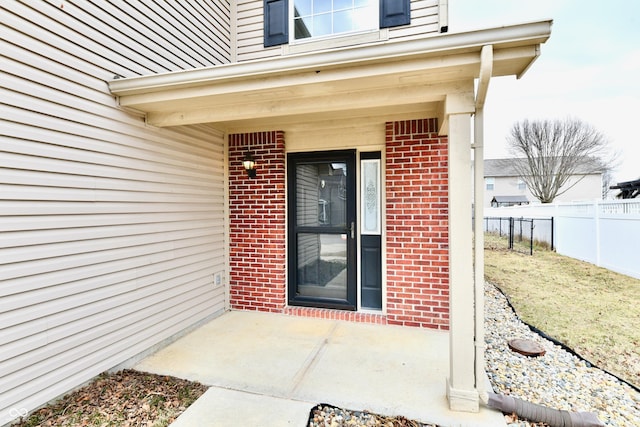 entrance to property with brick siding and fence