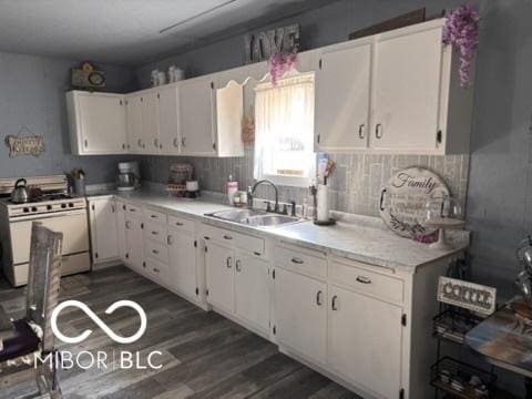 kitchen featuring white gas range oven, white cabinets, and a sink