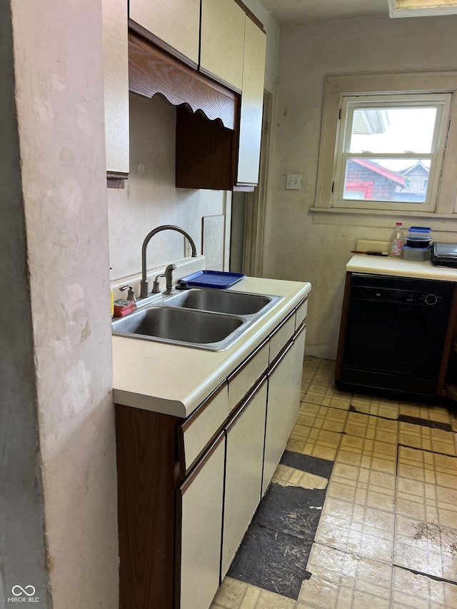 kitchen featuring light floors, black dishwasher, light countertops, and a sink