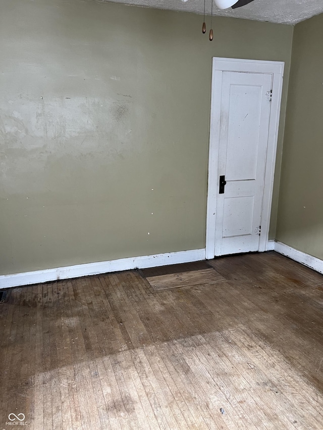 spare room featuring wood-type flooring and baseboards