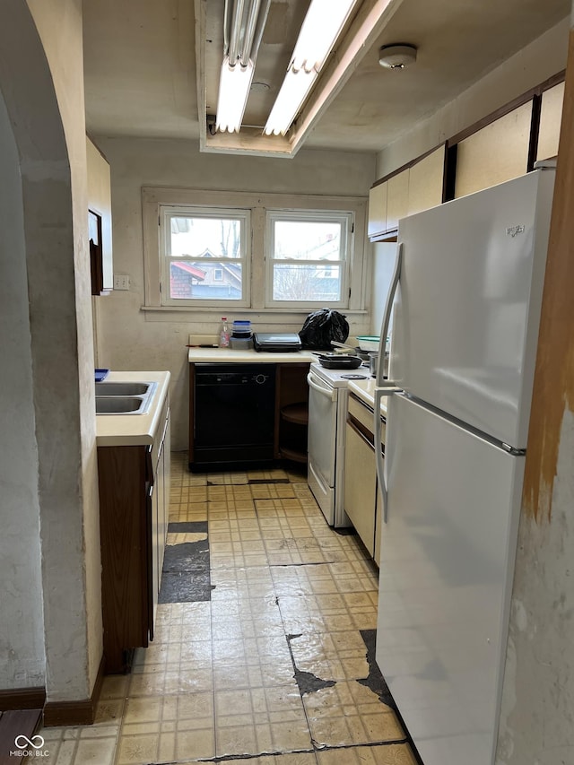 kitchen featuring white appliances, white cabinets, light countertops, light floors, and a sink