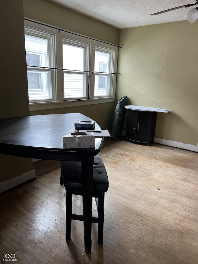 dining room with wood-type flooring, a ceiling fan, and a textured ceiling