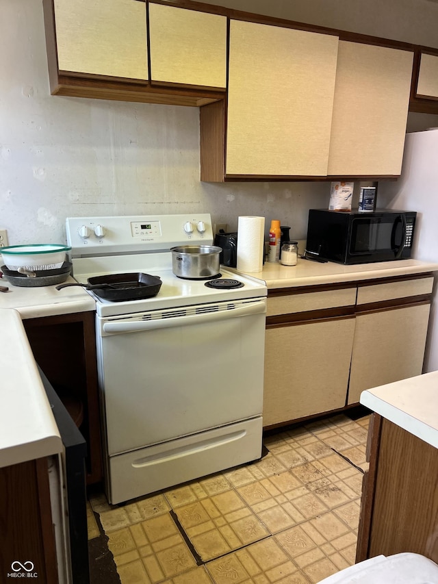 kitchen with black microwave, electric stove, and light countertops