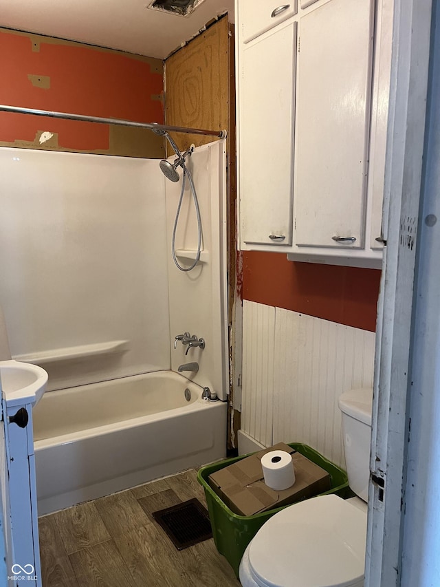 full bath featuring shower / bathing tub combination, wood finished floors, and toilet