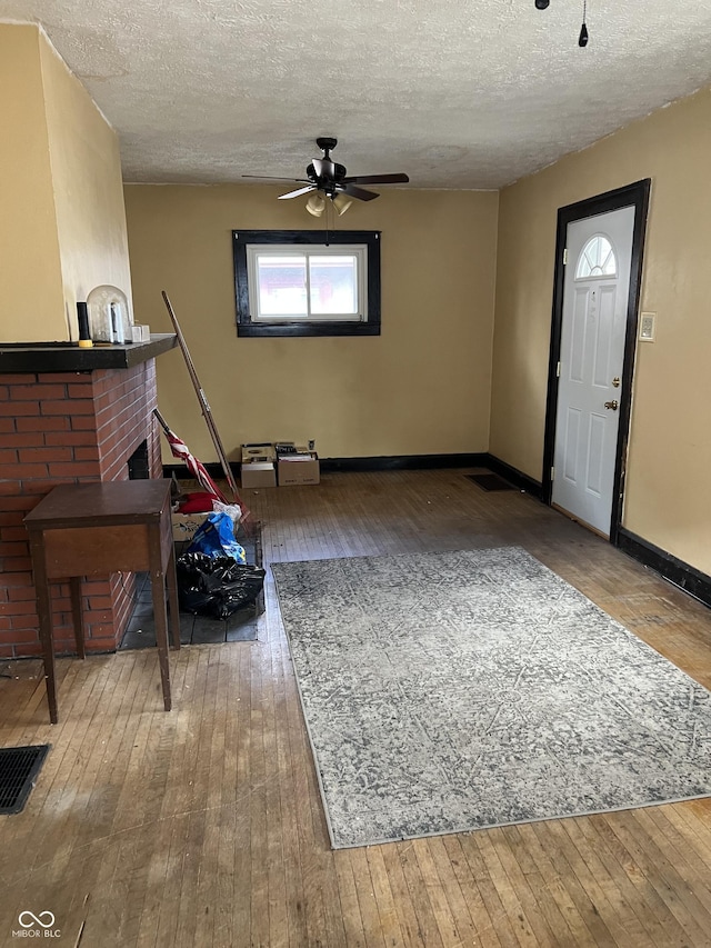 foyer with a fireplace, visible vents, a textured ceiling, baseboards, and hardwood / wood-style flooring