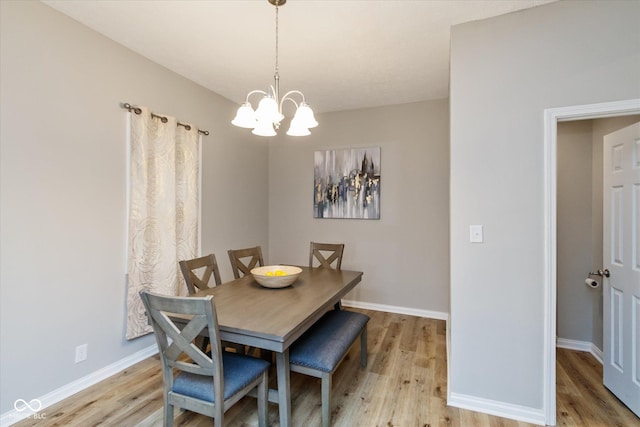 dining space with light wood-style floors, baseboards, and an inviting chandelier