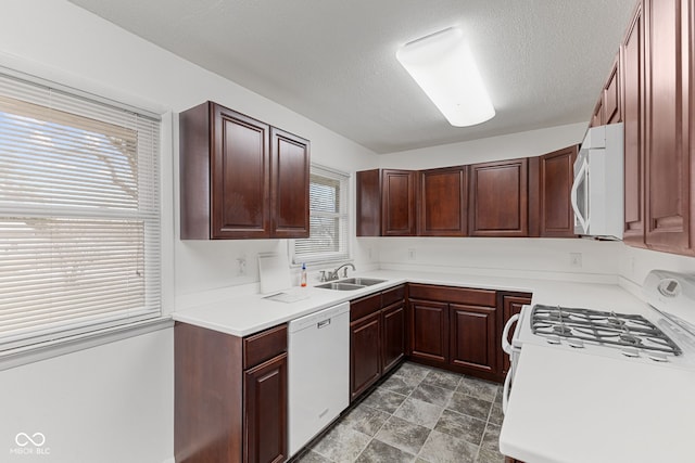 kitchen featuring white appliances, light countertops, a sink, and a textured ceiling