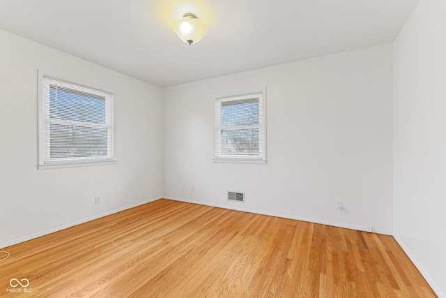 spare room with baseboards, visible vents, and light wood-style floors