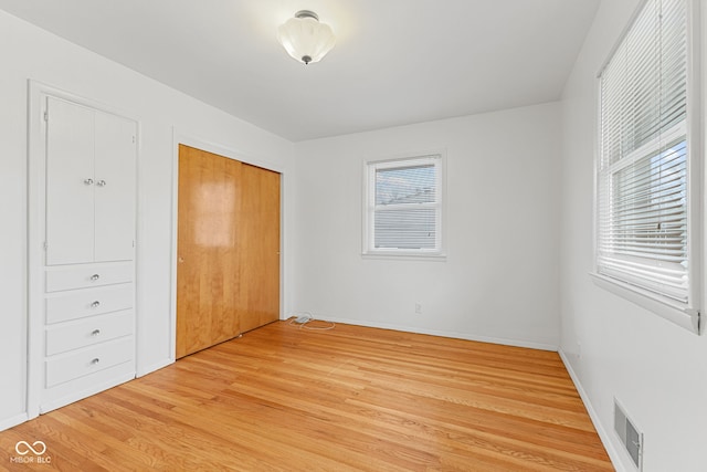 unfurnished bedroom with light wood-style flooring, a closet, visible vents, and baseboards