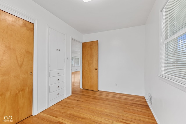 unfurnished bedroom with light wood finished floors, multiple windows, and baseboards