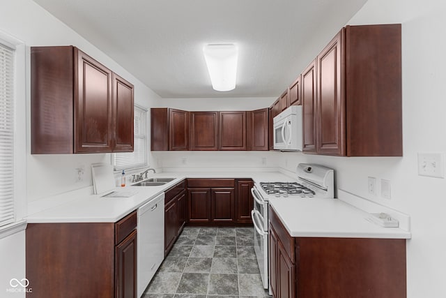 kitchen with a textured ceiling, light countertops, white appliances, and a sink