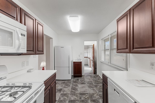 kitchen featuring a textured ceiling, light countertops, and white appliances