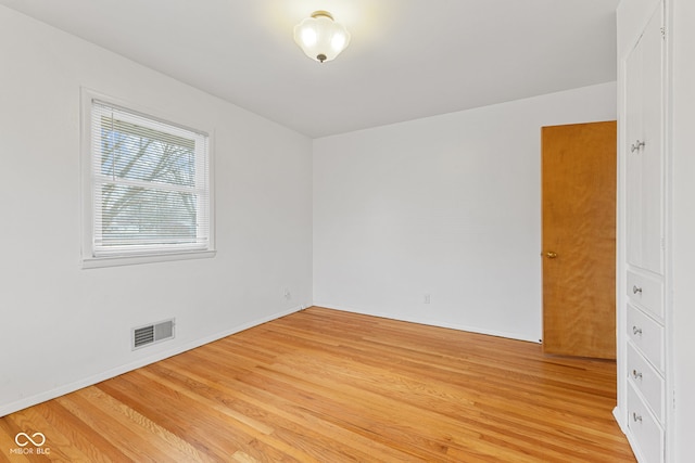 empty room featuring light wood-type flooring, visible vents, and baseboards