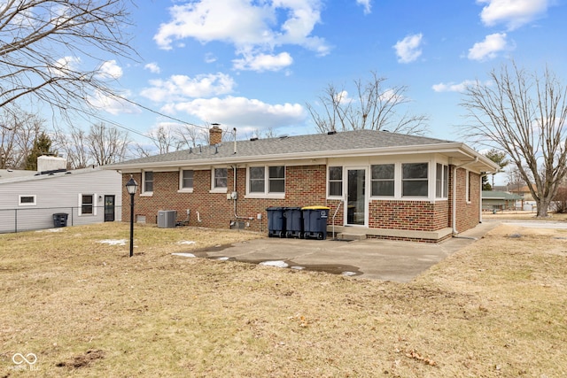 back of property with a chimney, a yard, central air condition unit, a patio area, and brick siding