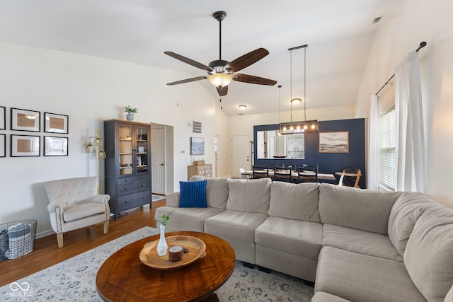 living area featuring visible vents, high vaulted ceiling, wood finished floors, and ceiling fan with notable chandelier