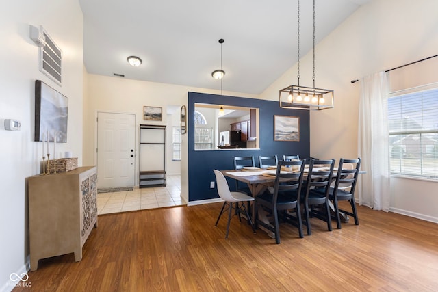 dining area featuring visible vents, baseboards, high vaulted ceiling, and wood finished floors