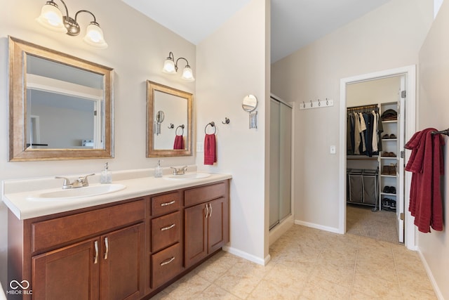 bathroom with a sink, a walk in closet, double vanity, and a shower stall