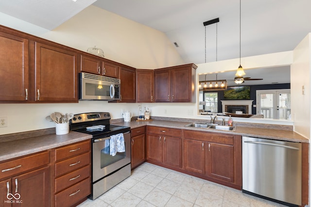 kitchen featuring a sink, dark countertops, stainless steel appliances, a fireplace, and vaulted ceiling