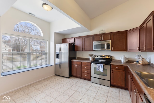 kitchen featuring visible vents, a sink, dark countertops, appliances with stainless steel finishes, and vaulted ceiling