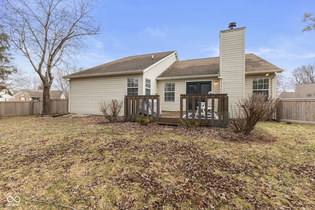 back of property with a chimney, fence private yard, and a deck