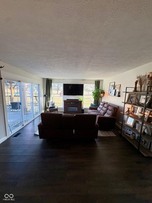 living area with a textured ceiling, wood finished floors, and visible vents