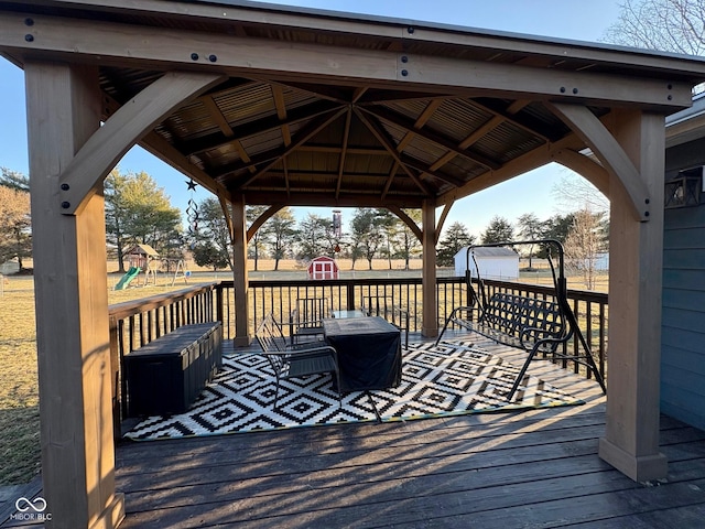 wooden deck with a gazebo, a storage unit, a playground, and an outdoor structure