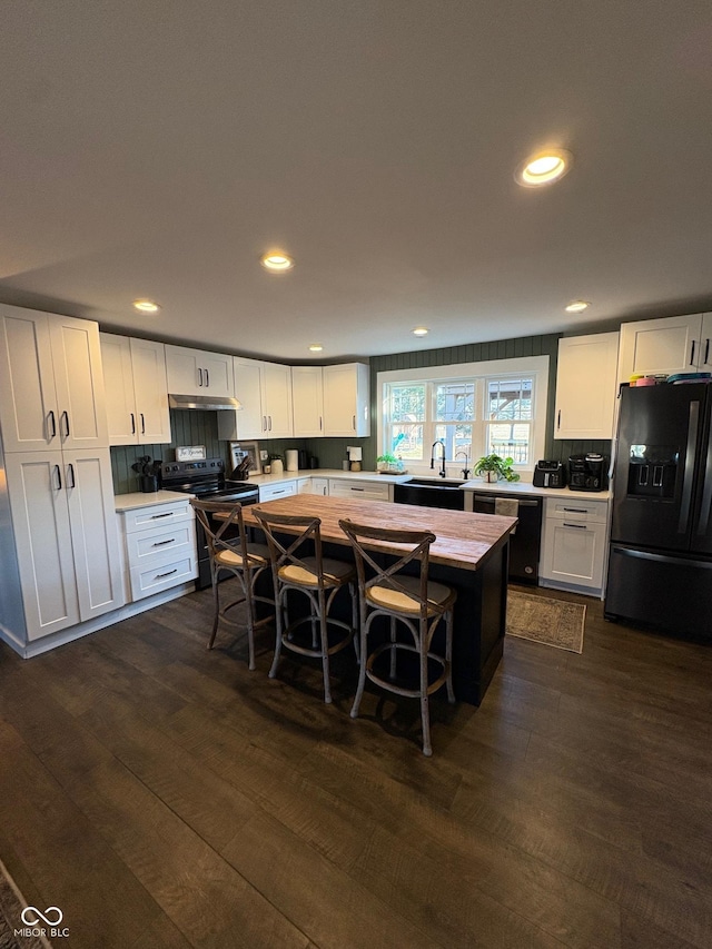 kitchen with dark wood-style floors, black refrigerator with ice dispenser, white cabinetry, range with electric cooktop, and dishwashing machine