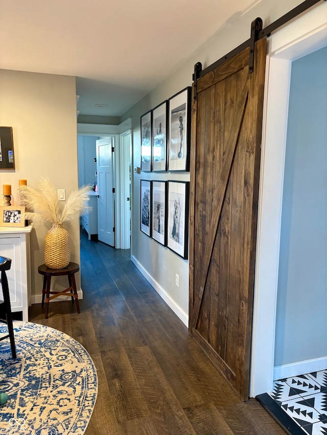 hallway with a barn door, baseboards, and wood finished floors