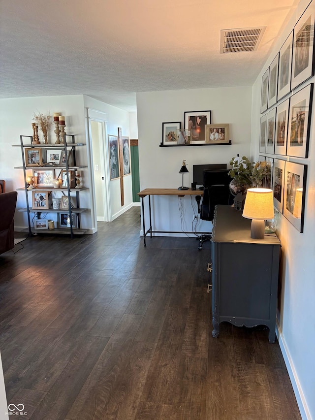 office area with dark wood-style floors, visible vents, and baseboards