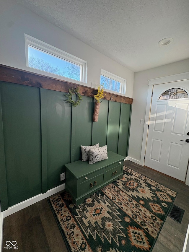 mudroom featuring a textured ceiling, wood finished floors, visible vents, and baseboards