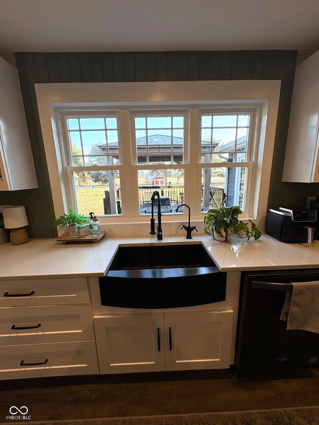 kitchen featuring light countertops, white cabinets, dishwasher, and a sink