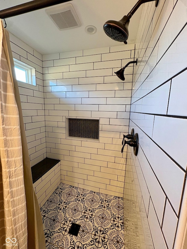 bathroom featuring visible vents, a tile shower, and tile patterned floors