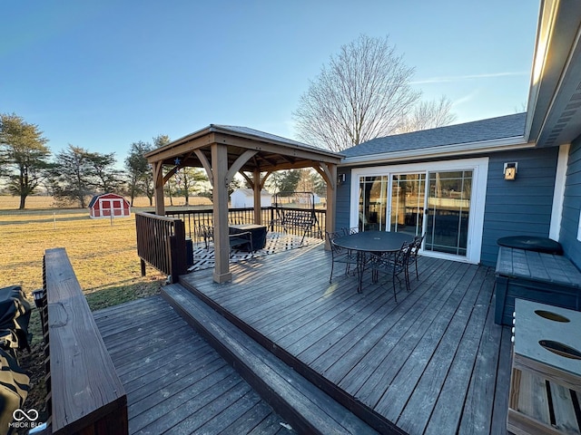 deck with a storage shed, a lawn, an outbuilding, a gazebo, and outdoor dining space