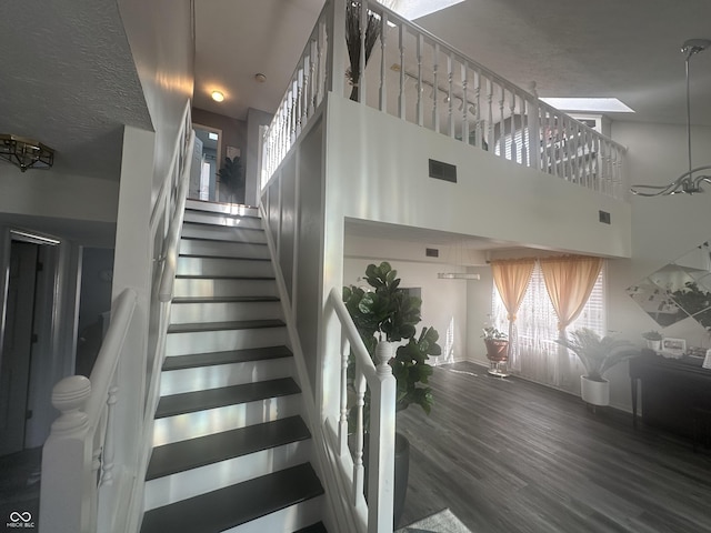 stairs with visible vents, a towering ceiling, and wood finished floors