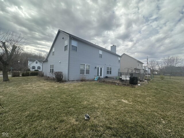 back of property with a chimney and a yard