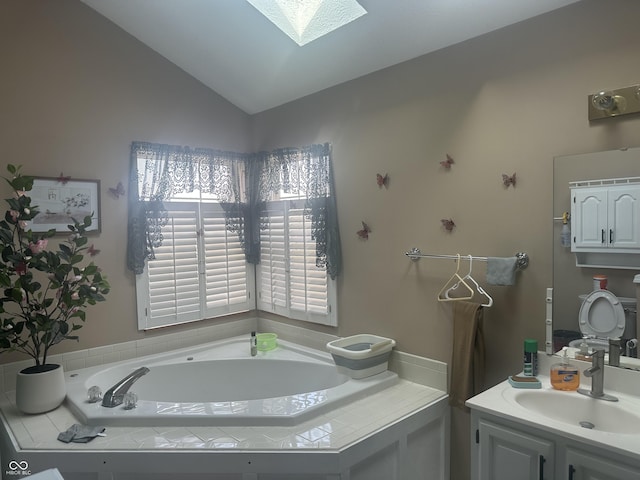 full bath featuring lofted ceiling with skylight, vanity, and a bath