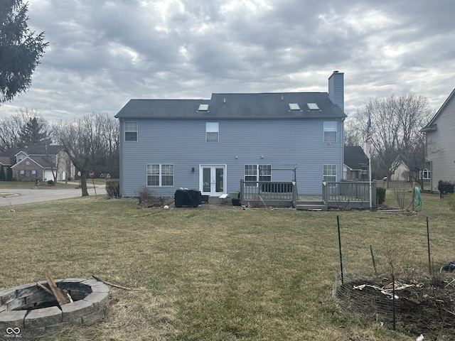 rear view of house with an outdoor fire pit, a yard, french doors, a wooden deck, and a chimney