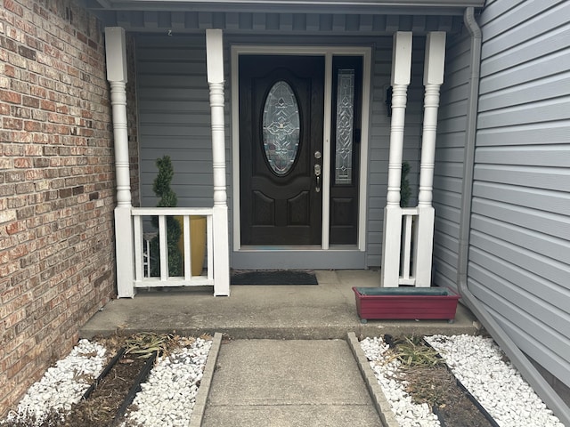 view of exterior entry with covered porch and brick siding