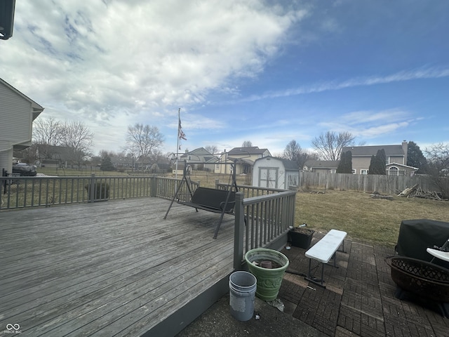 deck with an outbuilding, fence, a lawn, a residential view, and a shed