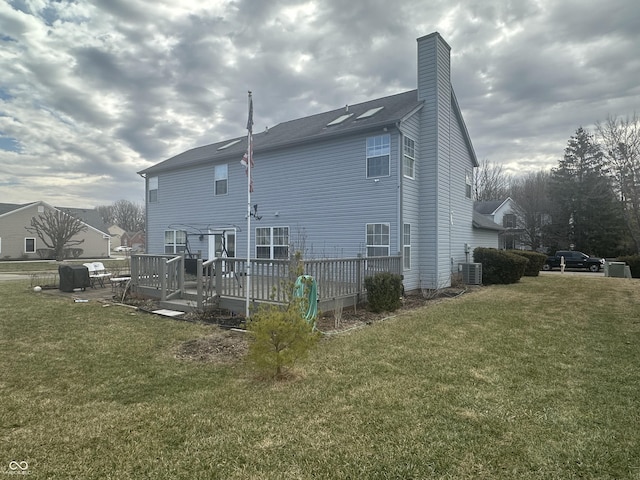 rear view of house with a yard, a chimney, a wooden deck, and central air condition unit