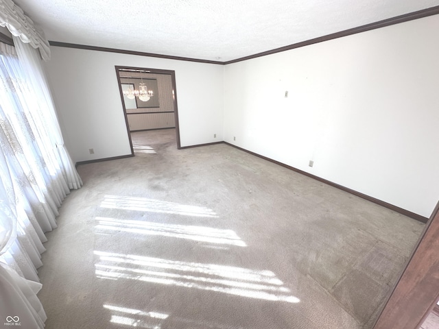 unfurnished room with crown molding, light colored carpet, an inviting chandelier, a textured ceiling, and baseboards